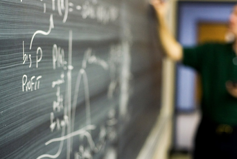 photo of faculty writing on chalkboard